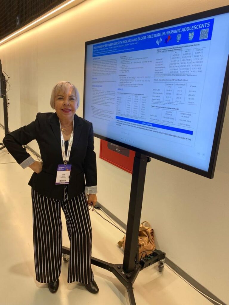 La doctora Eglé Silva, representante de Fundahipertensión, posa junto a un e-póster digital titulado "Relationship between obesity indexes and blood pressure in Hispanic adolescents", presentado en el 34th European Meeting on Hypertension and Cardiovascular Protection en Milán, Italia.